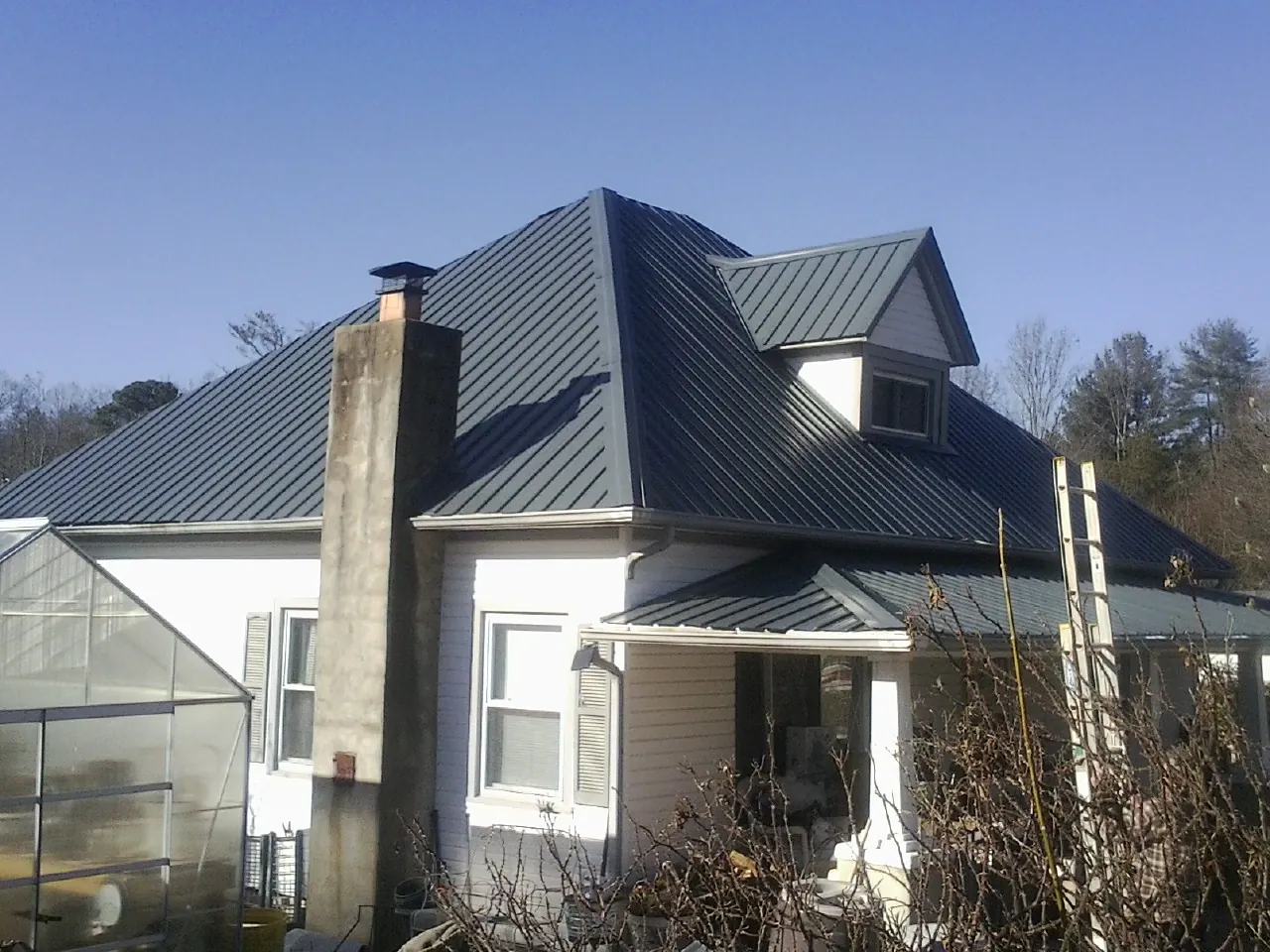 Dark blue standing seam metal roof on a white farmhouse with dormer — Slate & Tile Roof Repair by Roofing Brothers in Apache Junction